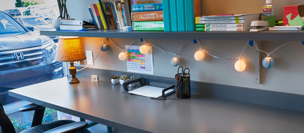 Clean desk work area with lamp and string lights.