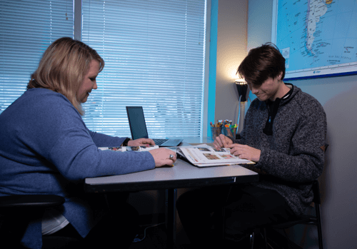 Student and teacher sitting with an open geography book.