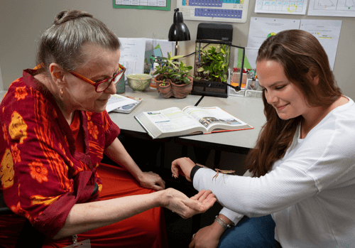 Teacher tutoring student while they are holding an insect.