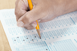 Hand holding a pencil while filling in an answer on a test.